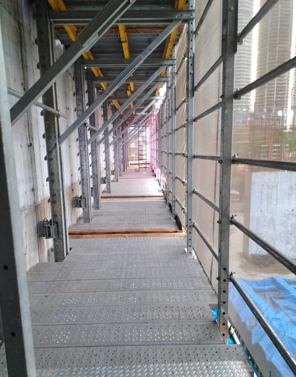 Access walkway along the safety screen and formwork edge on an active high-rise floor